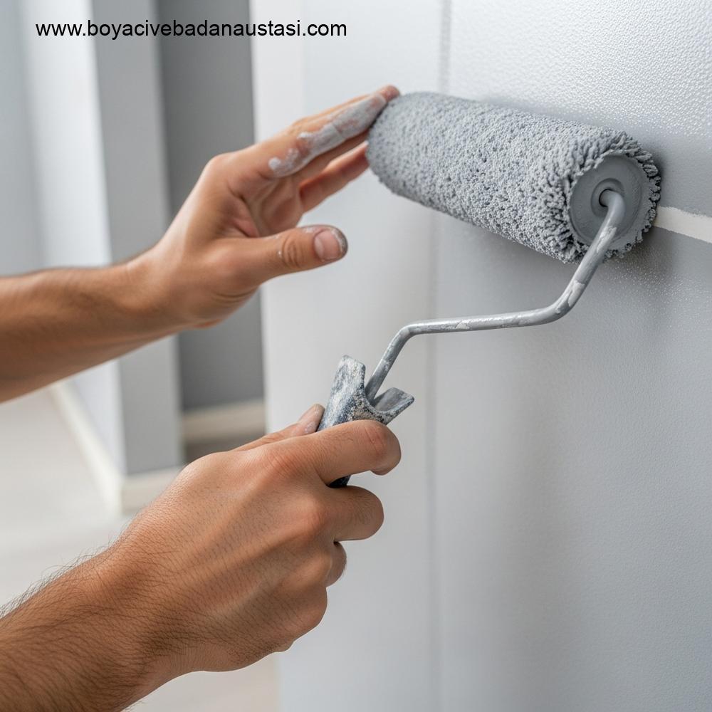 Profesyonel bir ustanın rulo ile açık gri iç cephe boyası uygularken el detayının yüksek çözünürlüklü yakın plan fotoğrafı.